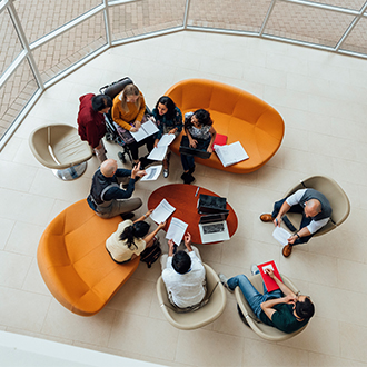 illustration - vue de dessus d'une réunion informelle sur des canapés orange et autour de tables basses